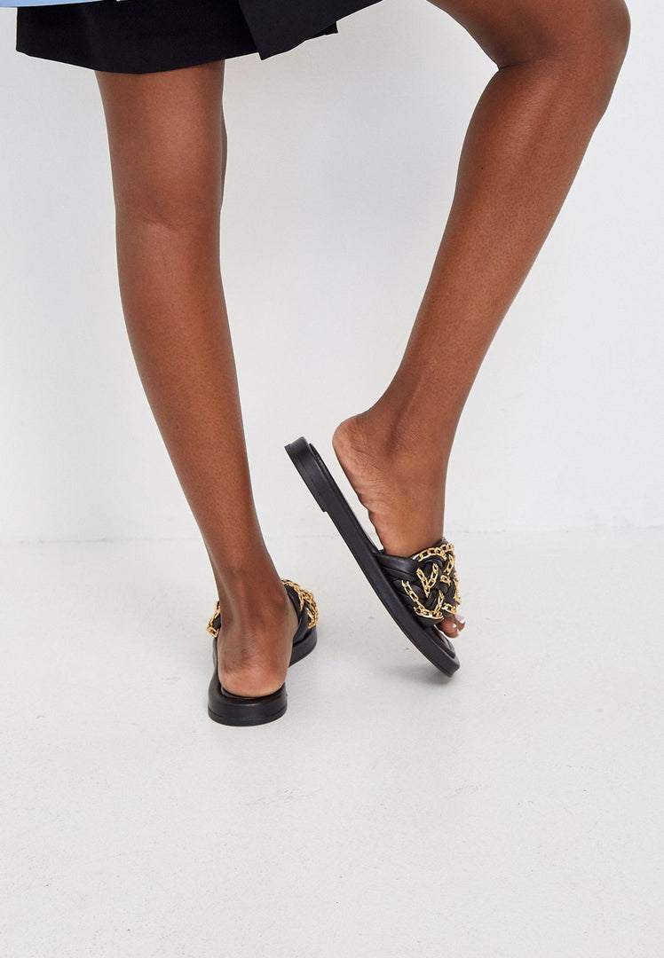 Close-up of fashionable black leather sandals with chain details, perfect for summer.