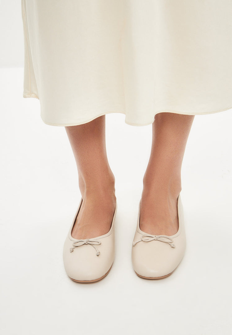 A stylish pair of ivory leather ballerina flats, perfect for any woman's wardrobe, these elegant slip-on shoes are a comfortable and chic choice for all occasions.
