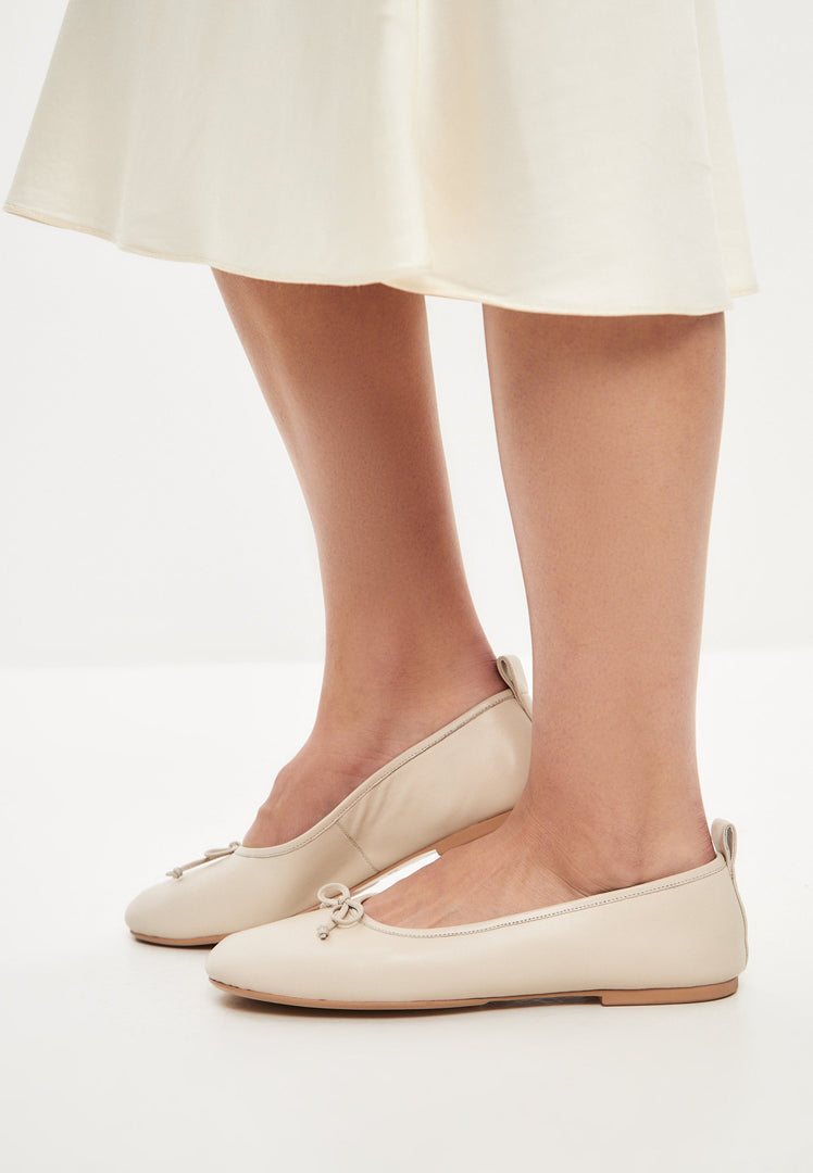A pair of elegant ivory leather ballerinas, perfect for women looking for stylish and comfortable leather flats or slip-on dress shoes.