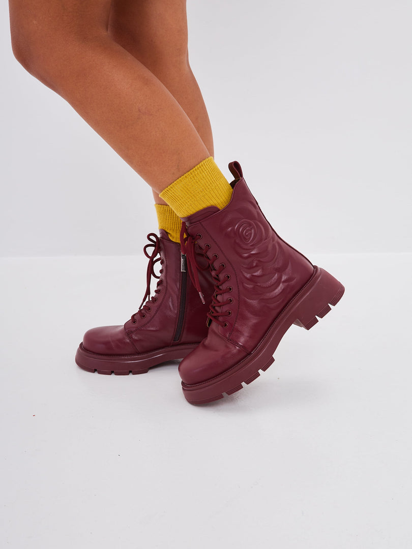 A stylish woman wearing fashionable high heel leather platform ankle boots in Bordeaux color.