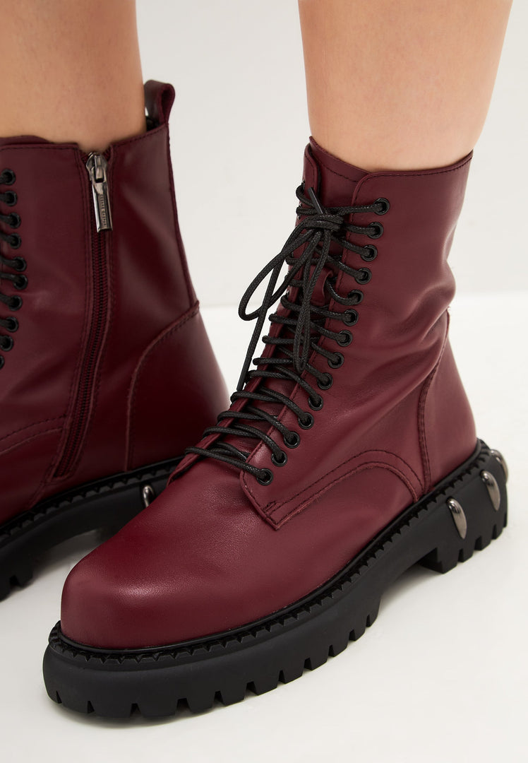 A pair of stylish lace-up combat boots with a chunky sole in a trendy bordeaux color, perfect for women's fashion footwear.