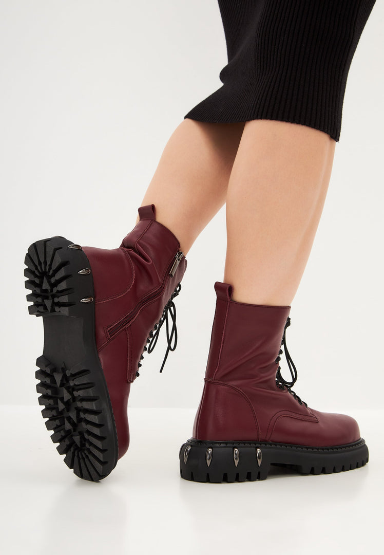 A pair of stylish lace-up combat boots with a chunky sole in rich Bordeaux color - trendy women's fashion footwear.