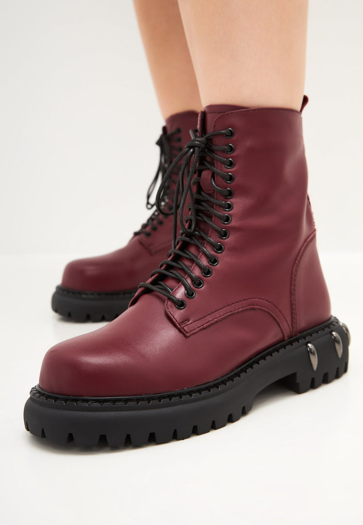 A stylish pair of women's lace-up combat boots with chunky soles in a rich Bordeaux color, perfect for fashion-forward individuals.