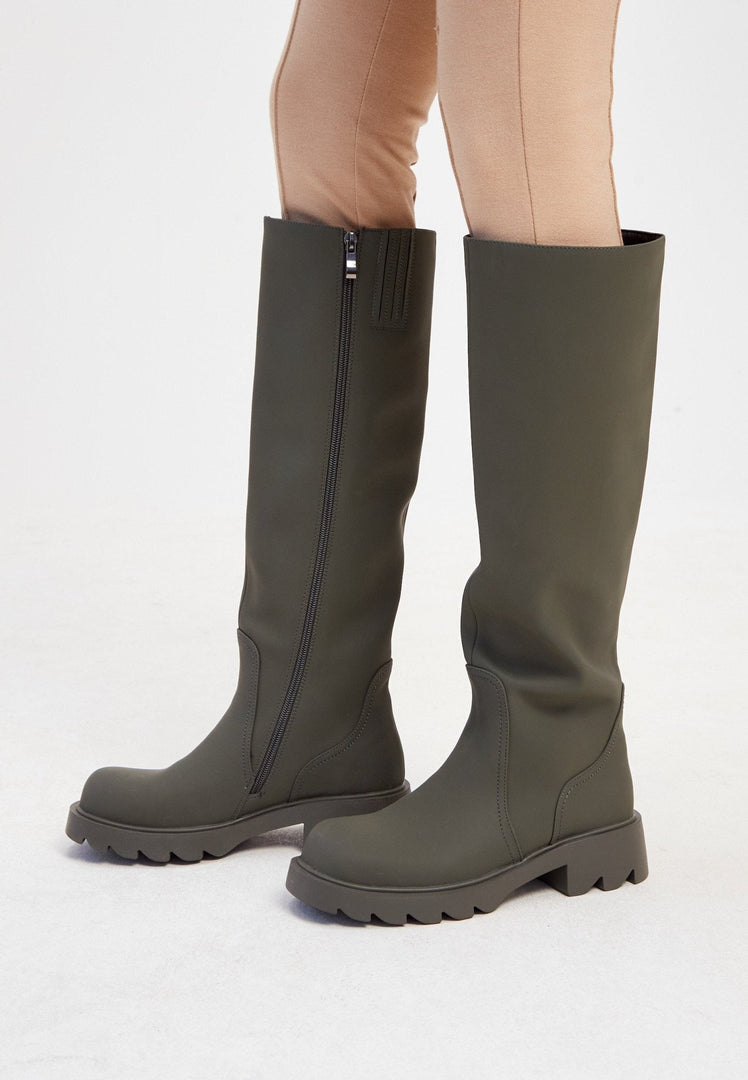 A trendy pair of knee-high chunky sole green boots, perfect for women's fashion footwear.