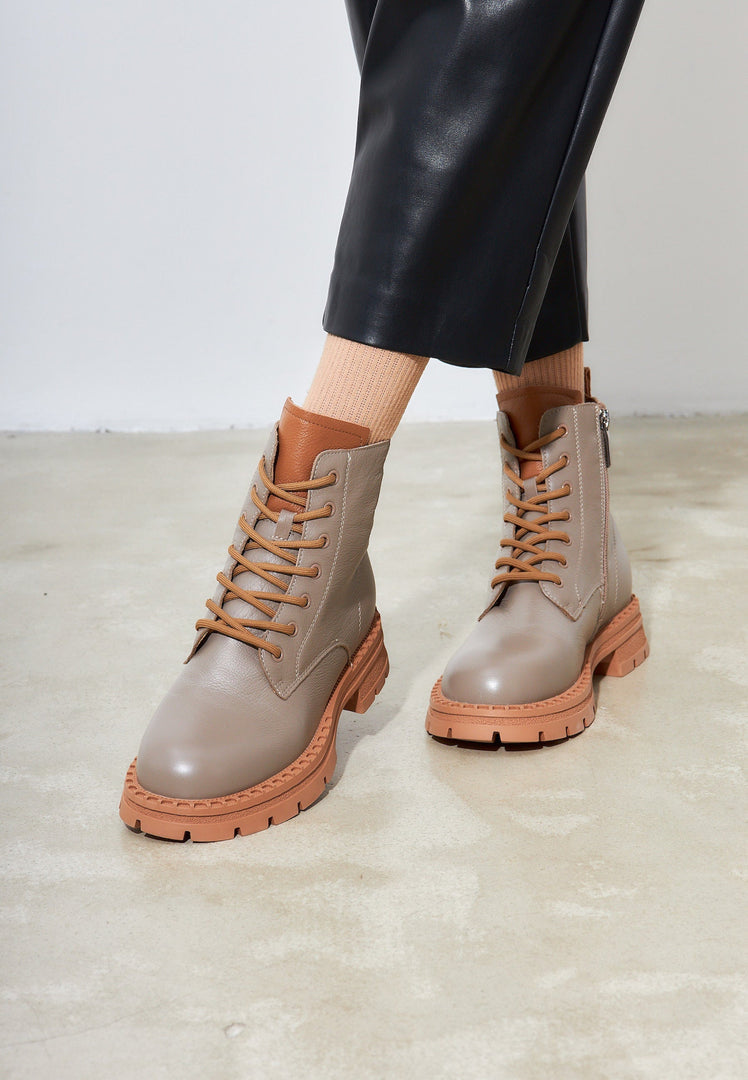 A stylish pair of lace-up leather ankle boots in beige, perfect for completing any women's fashion ensemble.
