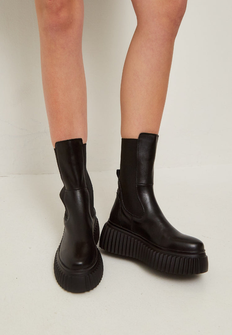 A stylish pair of black Chelsea boots with a ribbed sole, featuring a platform design, perfect for women's footwear fashion.