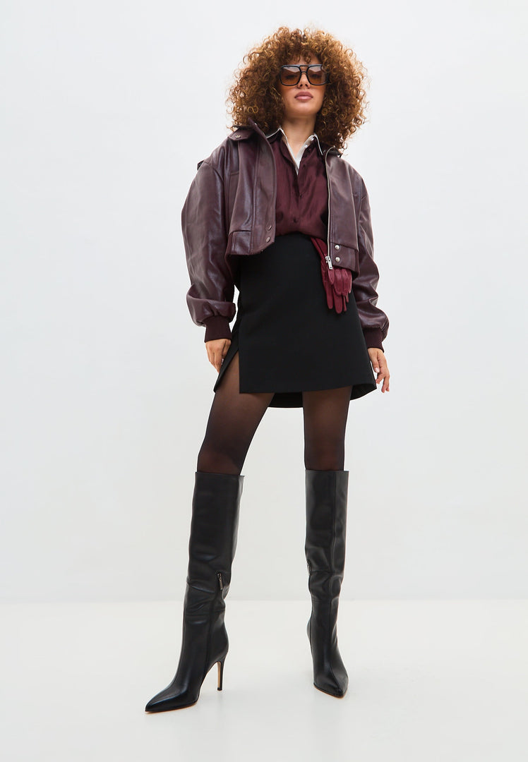 A chic pair of black leather knee-high boots with high heels, a timeless and sleek footwear choice that is on-trend with knee-high boot trends.