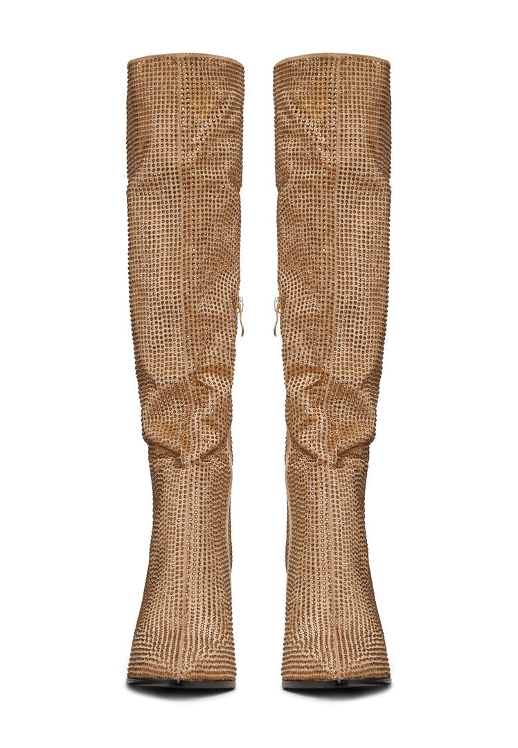 A close-up view of dazzling gold stiletto knee high boots with jewel embellishments, perfect for a glamorous evening out.