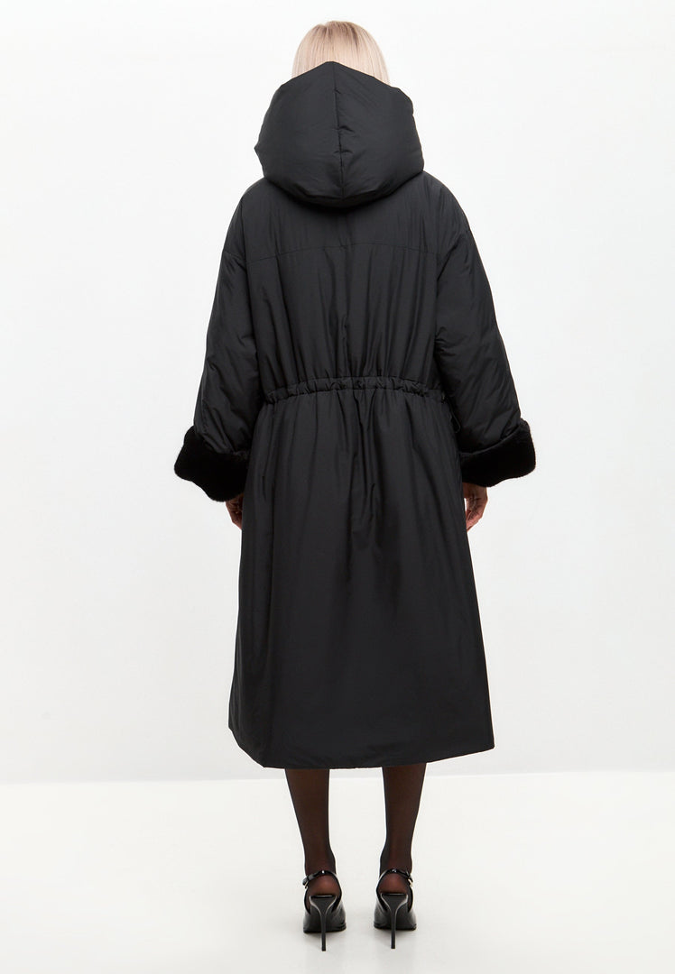 A stylish woman wearing an oversized black puffer coat with a hood, faux fur cuffs, and plus size fit, the perfect women's fashion jacket for winter.