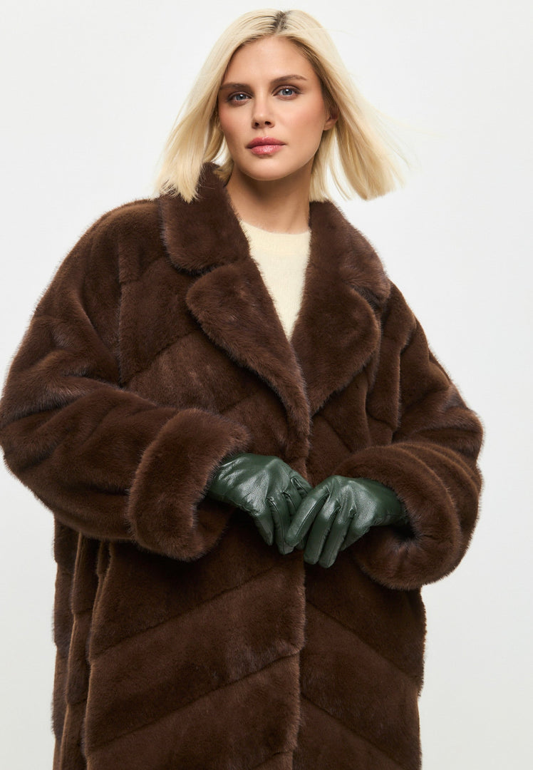 A sophisticated woman posing in an oversized brown faux fur coat, a trendy statement piece for winter fashion in women's outerwear.