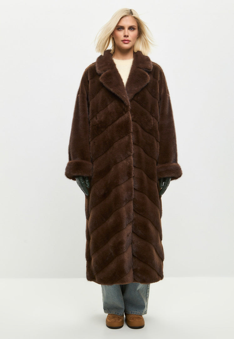 A fashionable woman wearing an oversized brown faux fur coat, a trendy statement piece for winter fashion in women's outerwear.