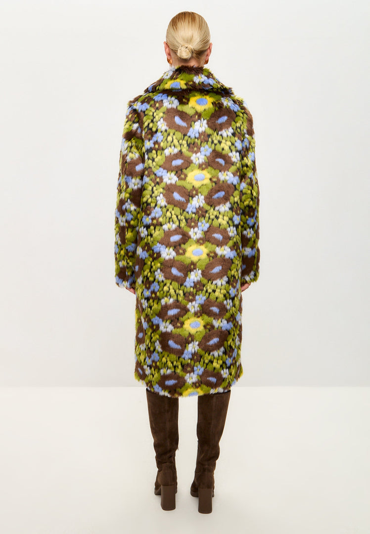 A stylish woman wearing a trendy faux fur coat with a vibrant floral print, accessorized for the season.