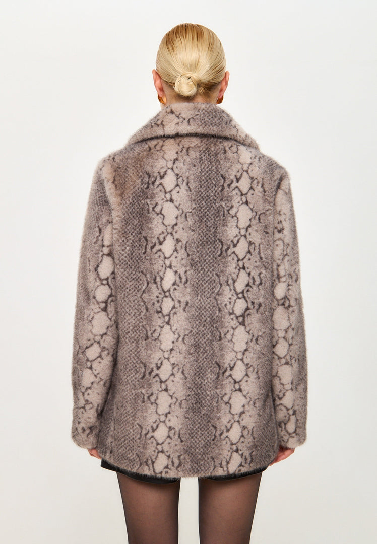 A fashionable woman wearing a beige faux fur Niuvis coat with snake print trim, a stylish outerwear choice for trendy winter fashion.