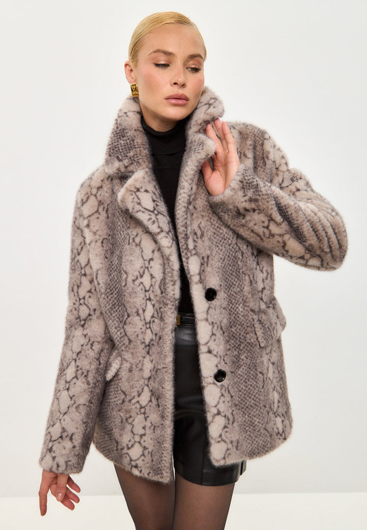 A model wearing a stylish snake print Niuvis coat, showcasing trendy winter fashion with a beige faux fur collar.